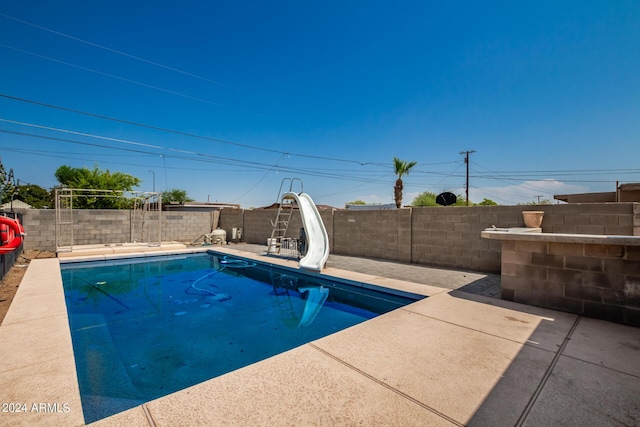 view of pool with a water slide and a patio