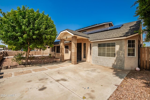 view of front of house with a patio area and solar panels