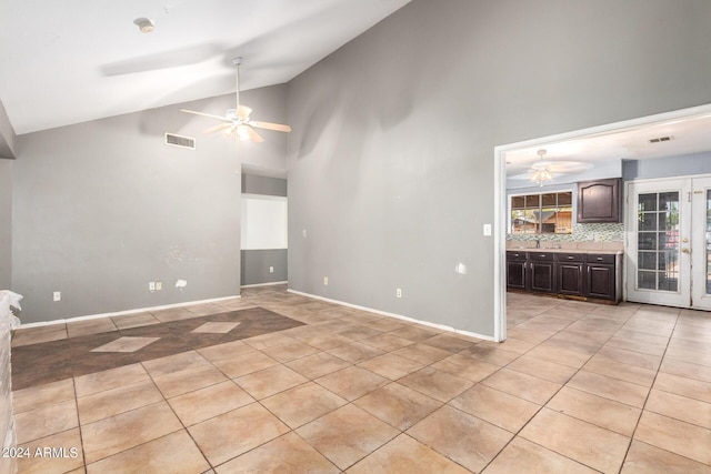 unfurnished living room with light tile patterned floors, high vaulted ceiling, and ceiling fan