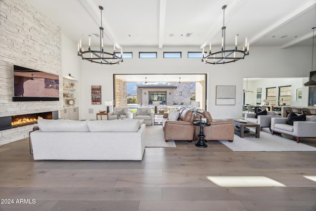 living room featuring built in shelves, a high ceiling, a stone fireplace, beamed ceiling, and wood-type flooring