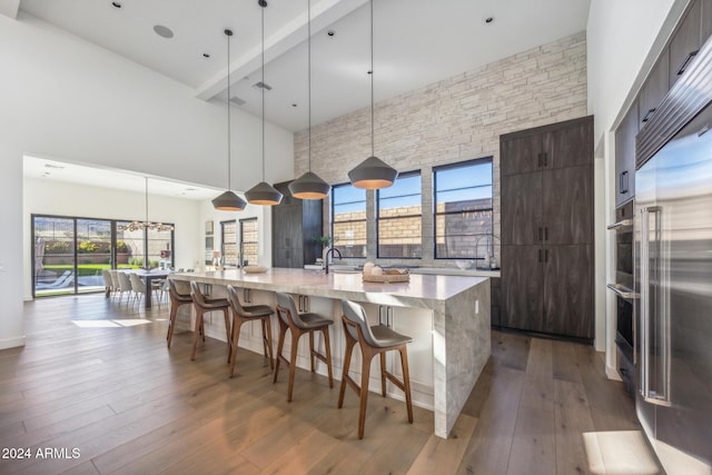 kitchen with a high ceiling, dark brown cabinets, hanging light fixtures, and a spacious island