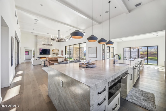 kitchen with a high ceiling, sink, a spacious island, and decorative light fixtures