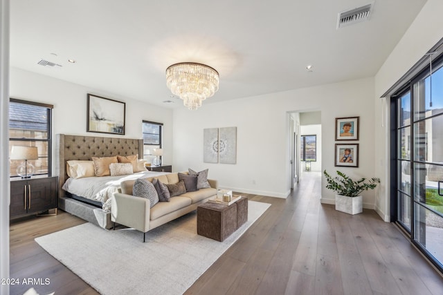 bedroom featuring a chandelier, light hardwood / wood-style floors, and multiple windows