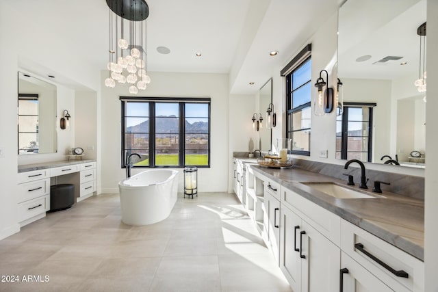 bathroom with a tub to relax in, tile patterned flooring, vanity, and a chandelier