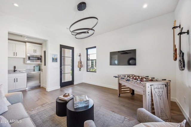 living room with light hardwood / wood-style floors, an inviting chandelier, and sink