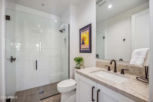 bathroom featuring tile patterned flooring, vanity, a shower with shower door, and toilet