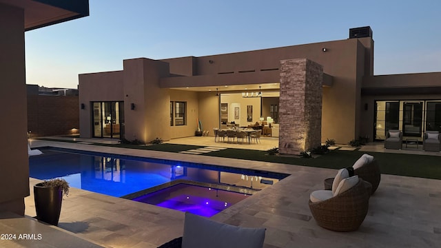 pool at dusk featuring an in ground hot tub and a patio