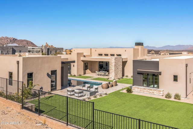 back of property featuring outdoor lounge area, a mountain view, a patio area, and a lawn