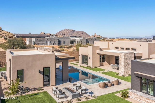 rear view of house featuring a fire pit, a mountain view, a pool with hot tub, and a patio area