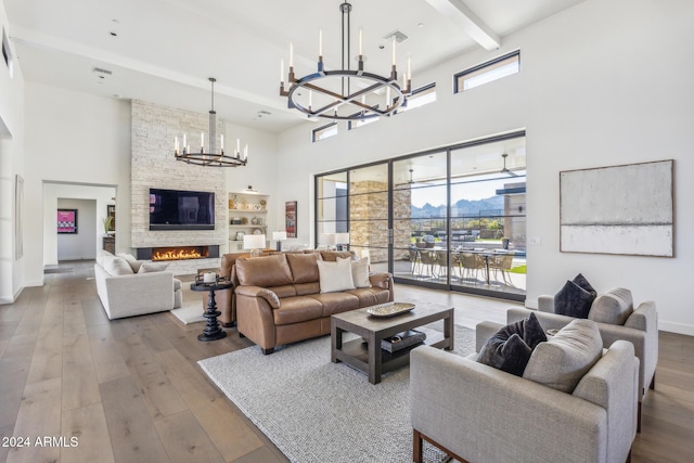 living room with a fireplace, a towering ceiling, light hardwood / wood-style flooring, and plenty of natural light