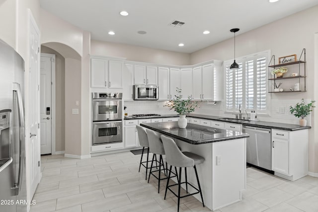 kitchen with appliances with stainless steel finishes, a kitchen bar, visible vents, and white cabinetry