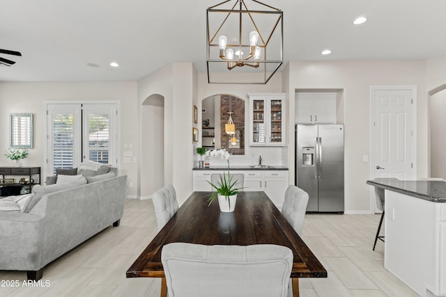 dining space featuring a dry bar, baseboards, arched walkways, and recessed lighting