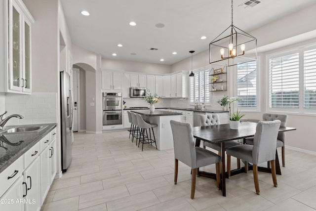 dining area featuring arched walkways, visible vents, baseboards, and recessed lighting