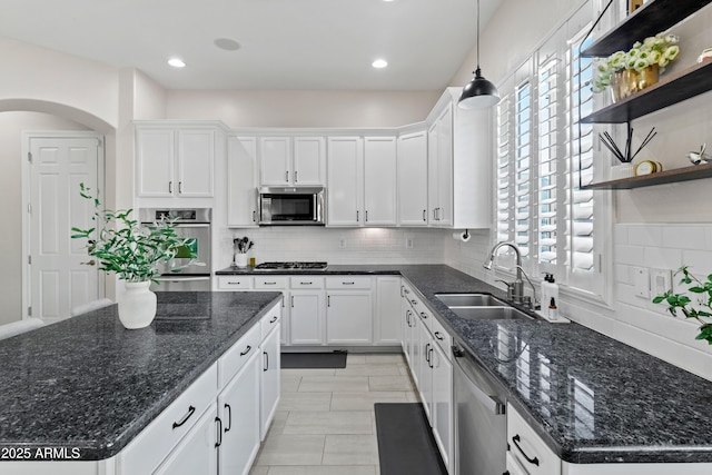 kitchen with arched walkways, appliances with stainless steel finishes, white cabinetry, open shelves, and a sink