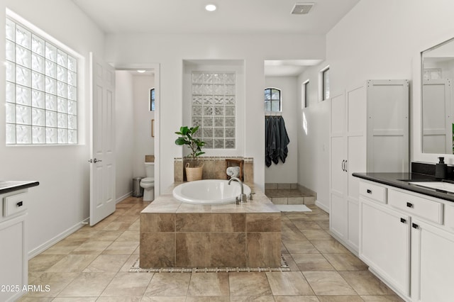 bathroom featuring toilet, a sink, visible vents, baseboards, and a bath