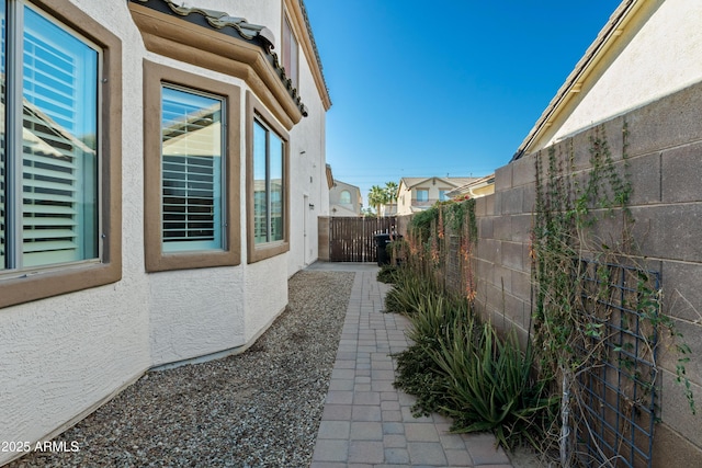 view of side of property featuring fence and stucco siding