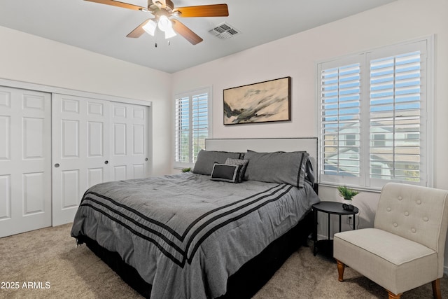 carpeted bedroom featuring a ceiling fan, visible vents, and a closet