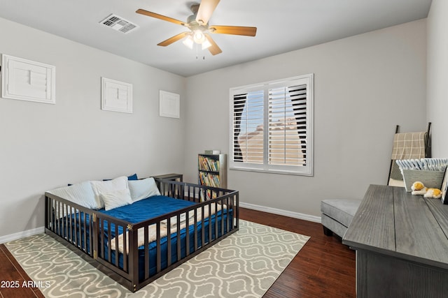 bedroom with dark wood-style floors, ceiling fan, visible vents, and baseboards