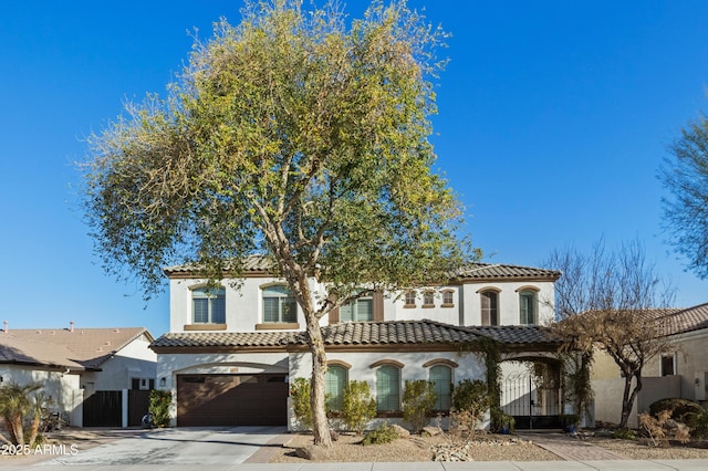 mediterranean / spanish-style house with a garage, a tile roof, concrete driveway, and stucco siding