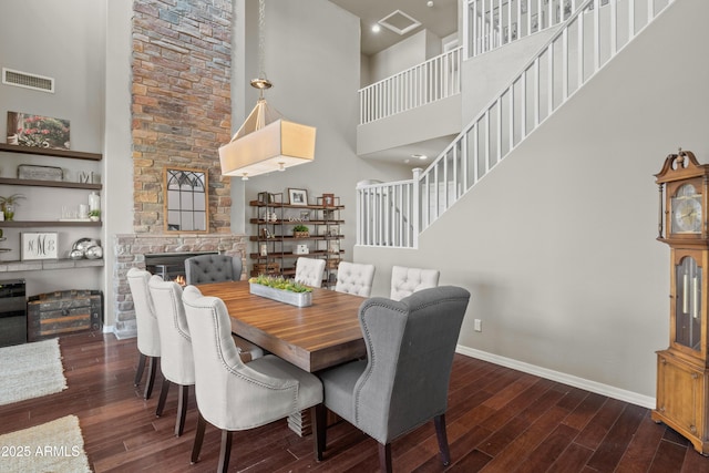 dining space with baseboards, a high ceiling, visible vents, and wood finished floors