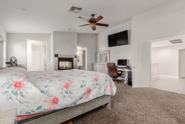 bedroom with a multi sided fireplace, light carpet, and ceiling fan