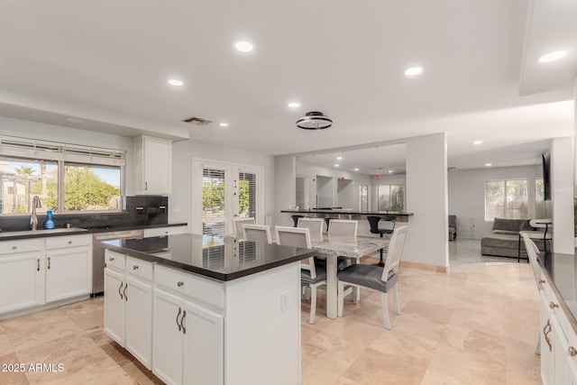 kitchen with sink, dishwasher, white cabinets, a kitchen island, and french doors