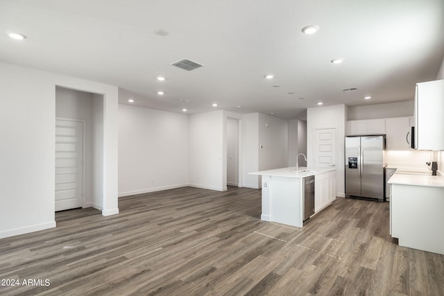 kitchen with stainless steel appliances, sink, hardwood / wood-style flooring, white cabinets, and an island with sink