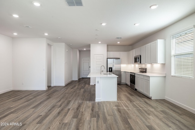 kitchen with a center island with sink, sink, hardwood / wood-style flooring, white cabinetry, and stainless steel appliances