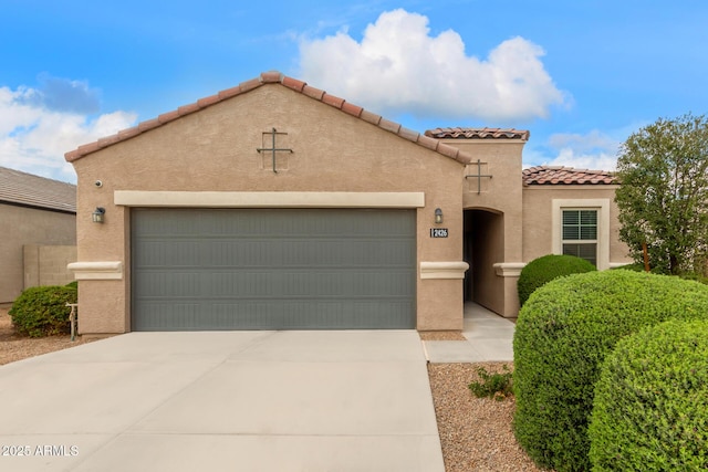 mediterranean / spanish house with stucco siding, a tiled roof, concrete driveway, and an attached garage