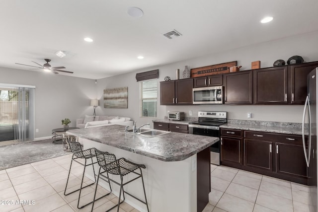 kitchen with visible vents, a sink, appliances with stainless steel finishes, a kitchen bar, and open floor plan