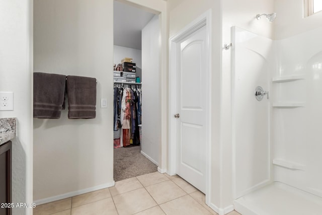 full bathroom featuring tile patterned floors, a walk in closet, vanity, and a walk in shower