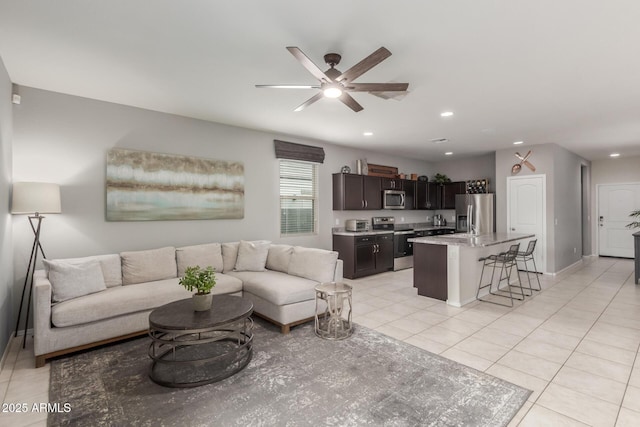 living area with light tile patterned floors, a ceiling fan, recessed lighting, and baseboards