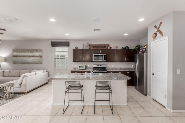 kitchen with visible vents, a sink, open floor plan, stainless steel appliances, and dark brown cabinetry