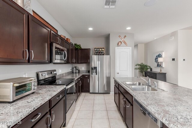 kitchen featuring light tile patterned floors, visible vents, a toaster, a sink, and stainless steel appliances