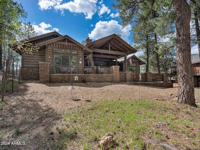 view of front of property featuring stone siding, a porch, and a chimney