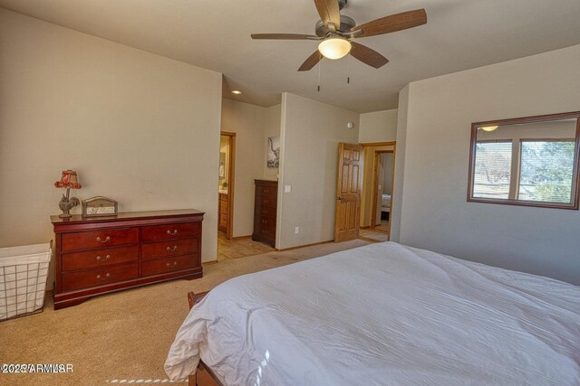 bedroom with light colored carpet, a ceiling fan, and ensuite bathroom