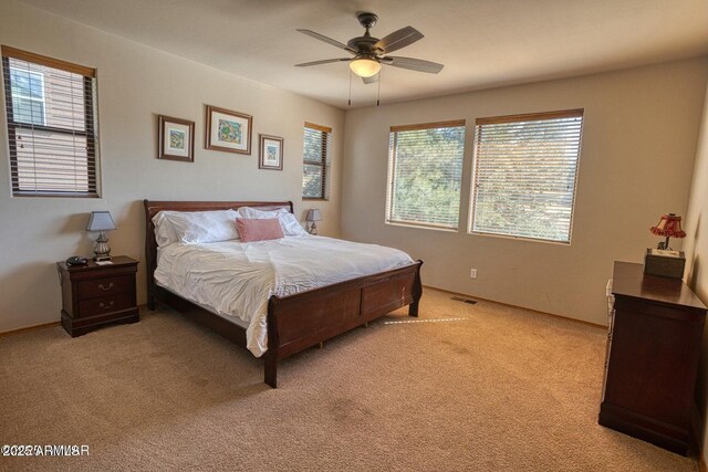 bedroom with light colored carpet, ceiling fan, and visible vents