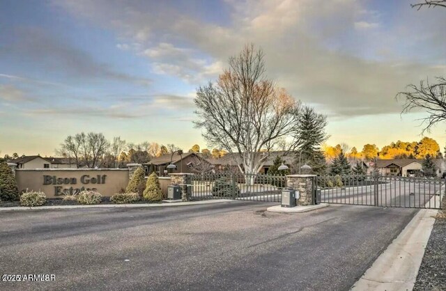 view of road featuring a gated entry, curbs, a gate, and a residential view