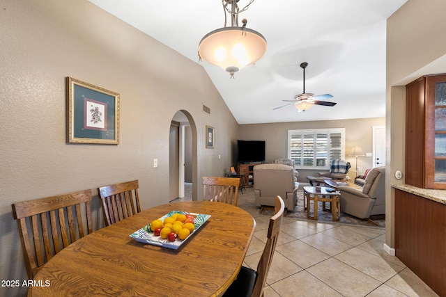 dining space with arched walkways, ceiling fan, lofted ceiling, light tile patterned flooring, and visible vents