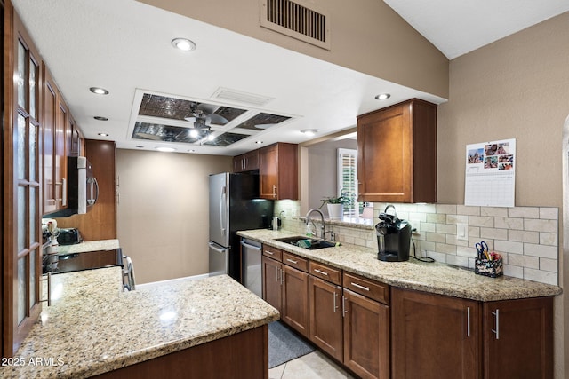 kitchen with visible vents, decorative backsplash, light stone countertops, stainless steel appliances, and a sink