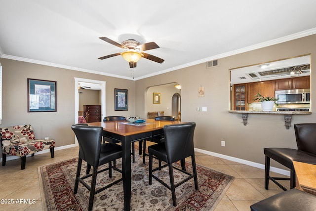 dining room featuring baseboards, visible vents, arched walkways, ornamental molding, and light tile patterned flooring