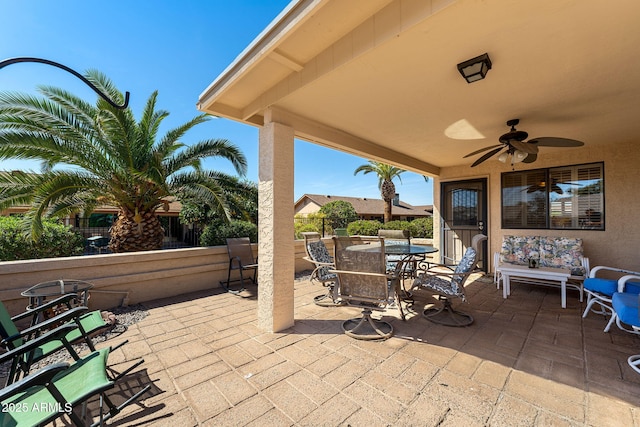 view of patio with outdoor dining space, ceiling fan, and fence