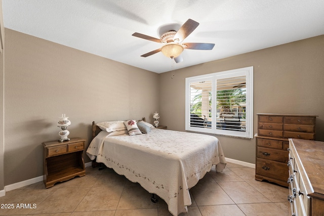 bedroom with ceiling fan, baseboards, and light tile patterned floors