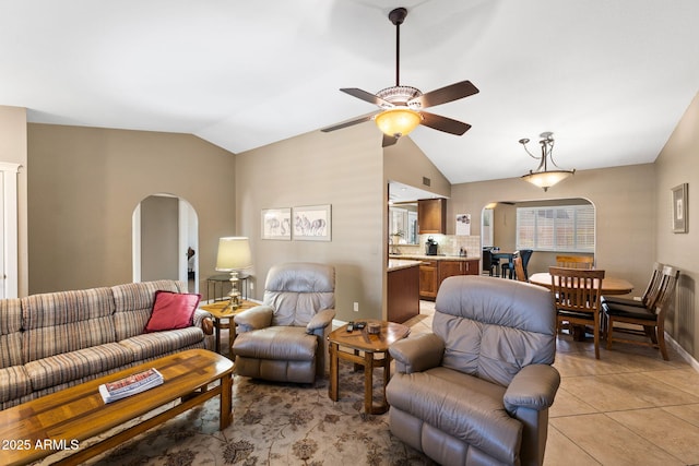 living area with lofted ceiling, light tile patterned floors, ceiling fan, and arched walkways