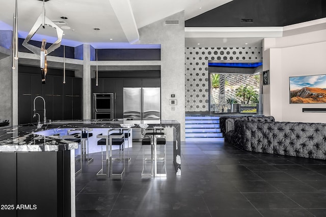 kitchen with stainless steel fridge, visible vents, high vaulted ceiling, and dark cabinets