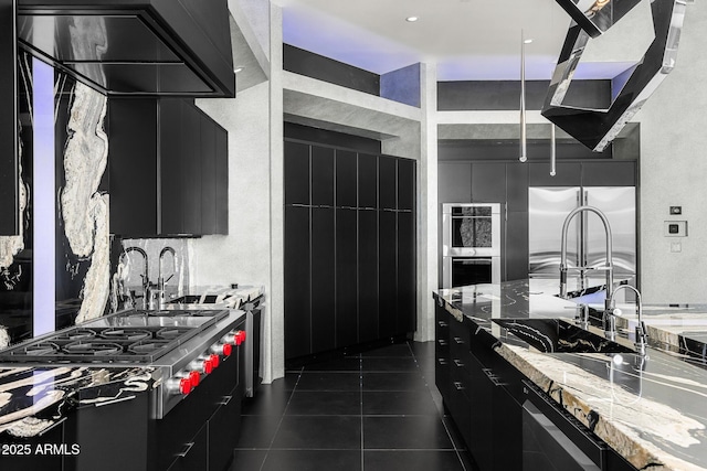 kitchen with stainless steel appliances, dark tile patterned flooring, a sink, dark cabinetry, and modern cabinets