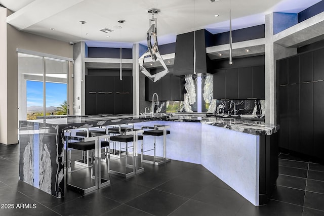 kitchen with visible vents, modern cabinets, dark cabinets, hanging light fixtures, and backsplash