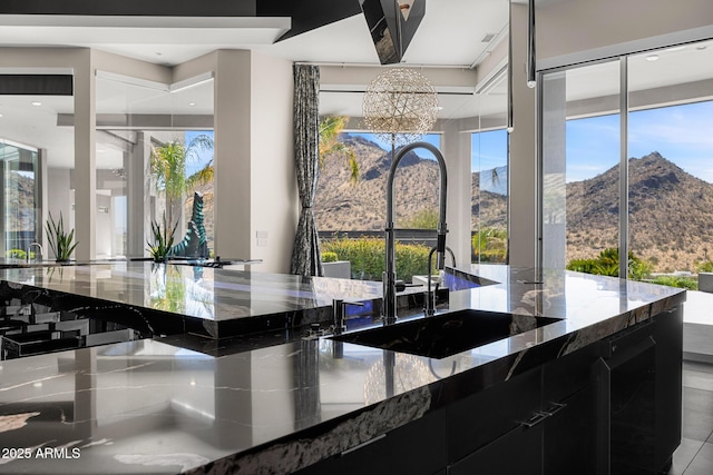 interior space with stone counters, an inviting chandelier, a sink, modern cabinets, and dark cabinets