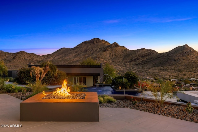 view of front of house featuring an outdoor fire pit, stucco siding, a mountain view, and a patio