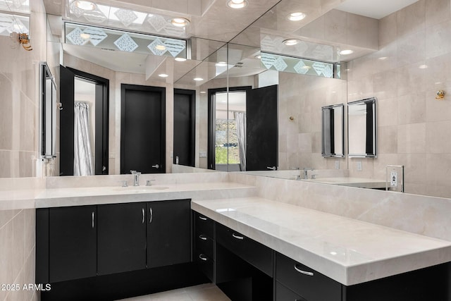 full bath featuring tile patterned flooring, vanity, and tile walls